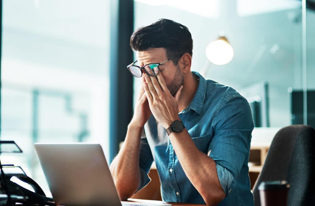Headache, stress and tired business man at laptop in office for anxiety, debt crisis and eye strain problem. Burnout, fatigue and worker at computer with pain, brain fog and frustrated with mistake.