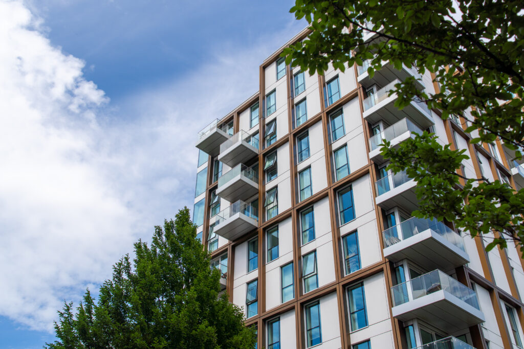 Valuations and Building Safety: Getting the Full Picture modern apartment building with balconies under cloudy blue sky surrounded by green trees